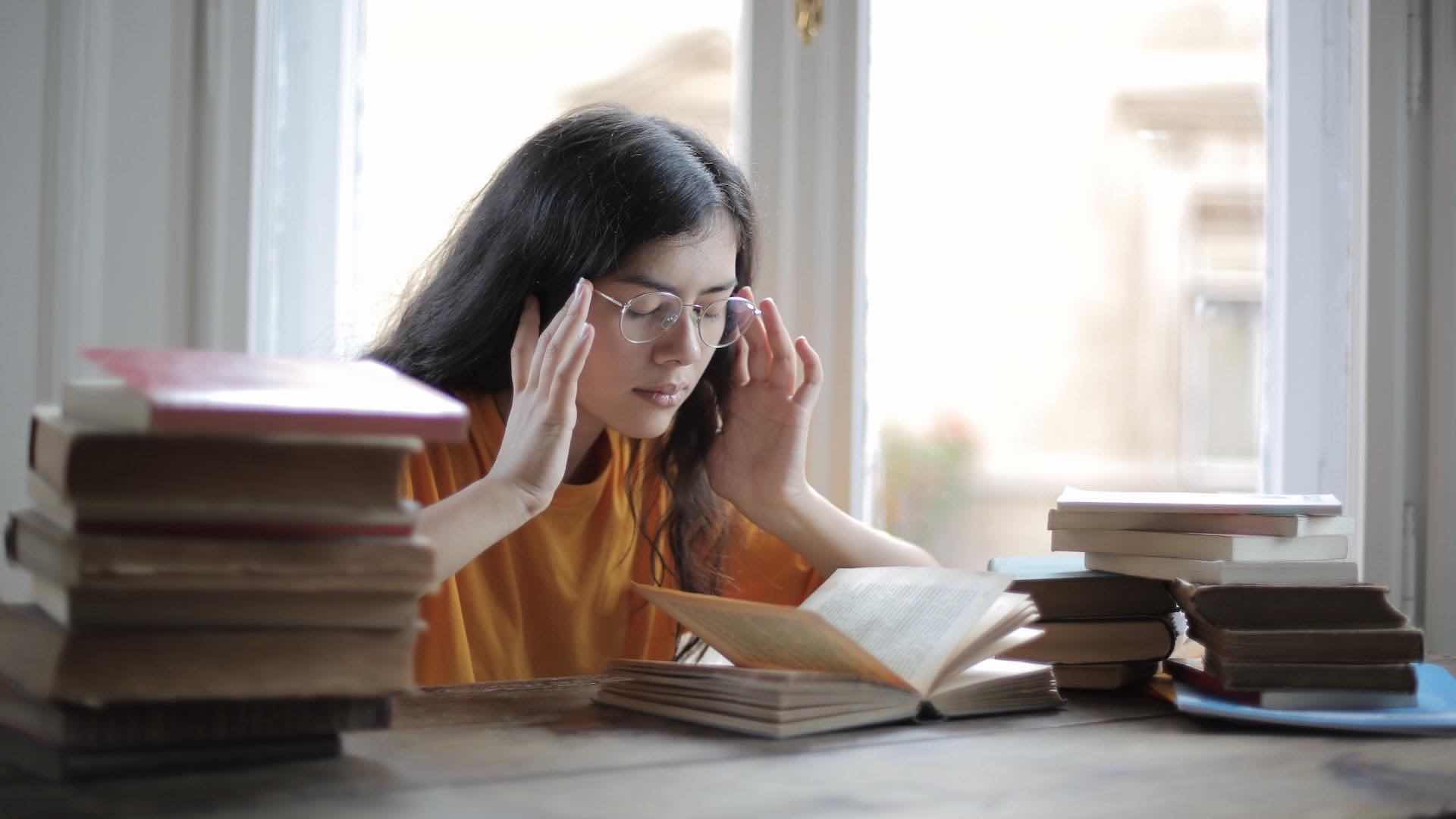 girl reading a book looking like she is having problem concentrating