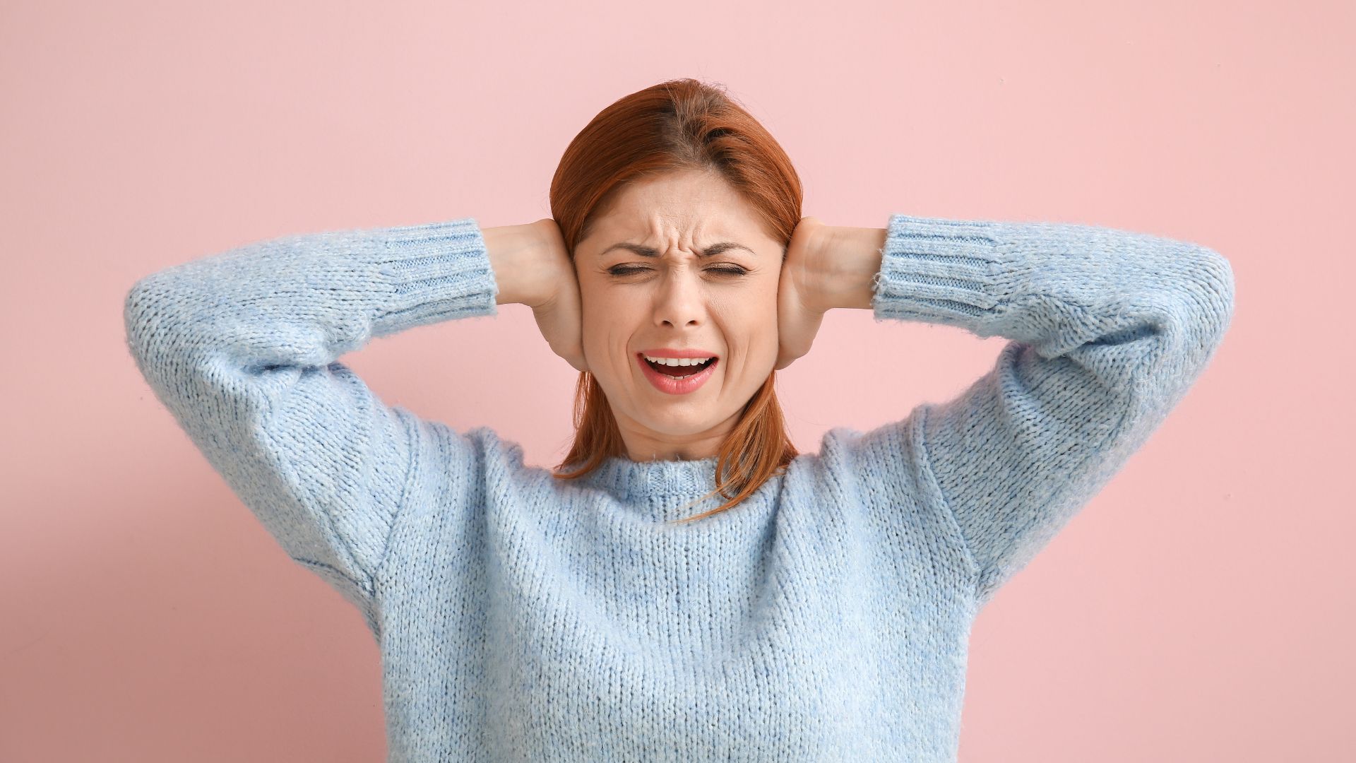 woman covers her ears in pain